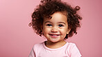 Portrait of a toddler posing against a pink background. happy smiling girl