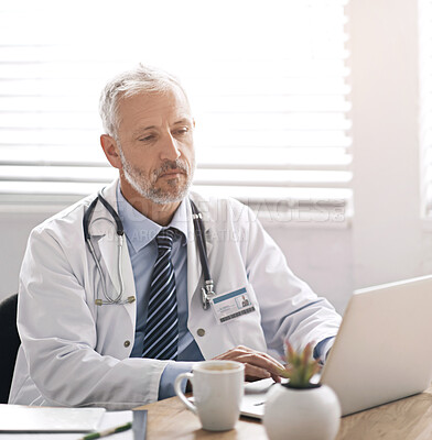 Buy stock photo Cropped shot of a mature male doctor working at his desk