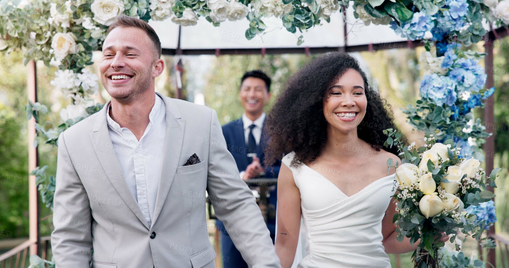 Buy stock photo Couple, wedding and walk with flower confetti for event, celebration and outdoor in nature. Girl, happy interracial marriage and floral bouquet in park, holding hands or fist in air, pride or party