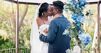 Black couple, wedding and kiss for love, marriage or commitment in embrace or hug together. Married African woman and man kissing affection, trust or relationship of bride or groom in outdoor romance