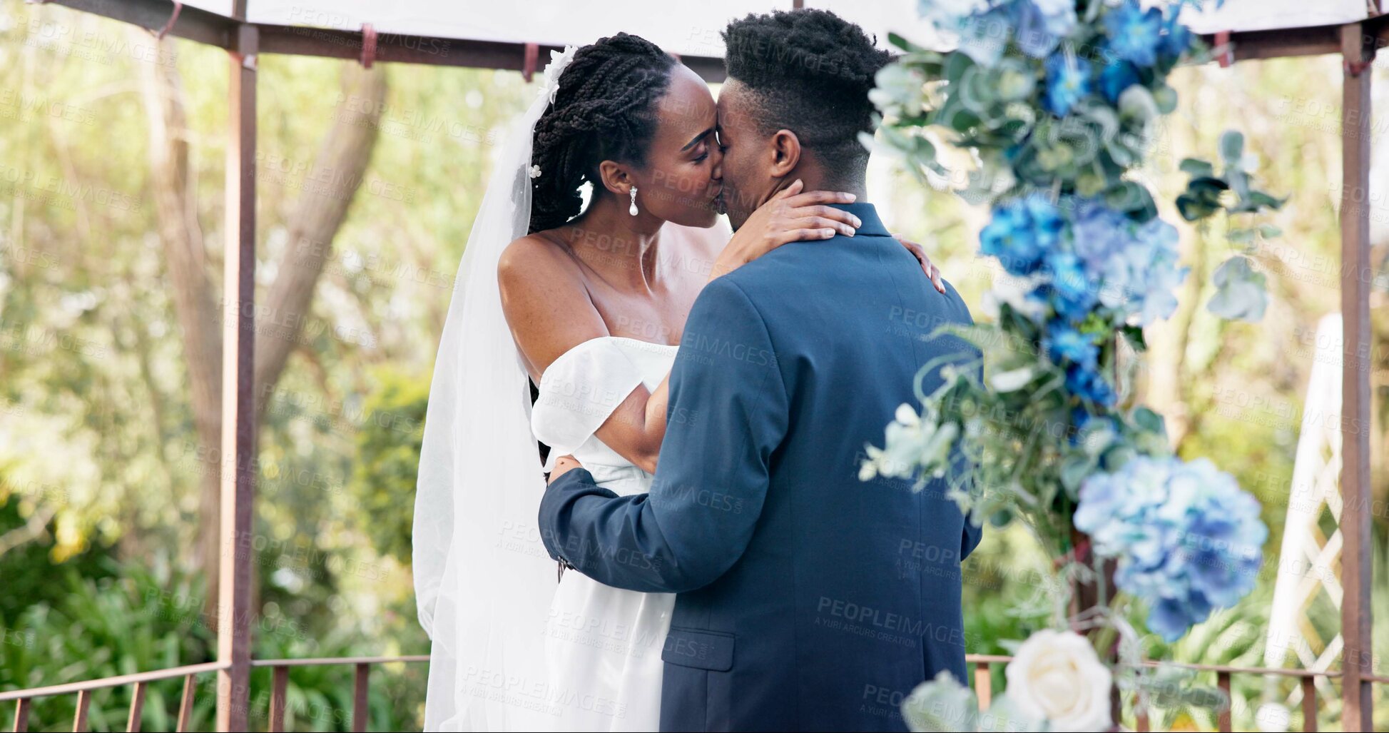 Buy stock photo Black couple, wedding and kiss for love, marriage or commitment in embrace or hug together. Married African woman and man kissing affection, trust or relationship of bride or groom in outdoor romance