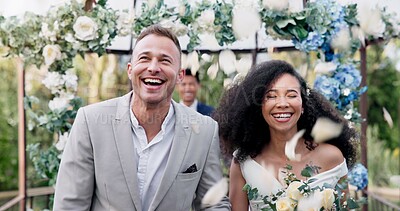 Couple, wedding and walk with flower confetti for event, celebration and outdoor in nature. Girl, happy interracial marriage and floral bouquet in park, holding hands or fist in air, pride or party