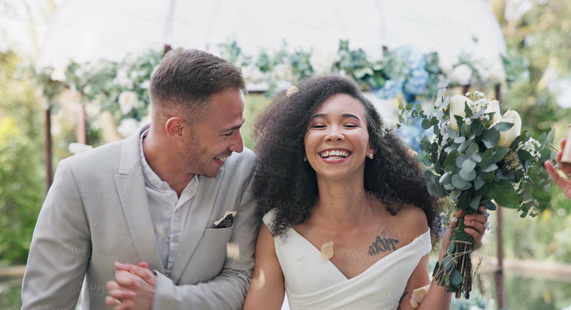 Buy stock photo Couple, wedding and celebration with flower confetti for event, walk and outdoor in nature. Girl, happy interracial marriage and floral bouquet in park, holding hands or applause from crowd in aisle