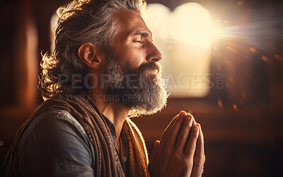 Mature religious man praying to God in room. Sun shining through window. Religious concept.