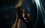 Portrait of young muslim woman bowing her head in prayer in dark room. Religion concept.