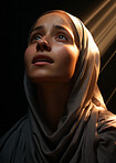Young muslim woman lifting her head in prayer. Sunlight on her face. Religion concept.