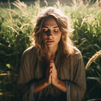 A woman prays against the backdrop of tall grass. Sunset, peaceful, nature. Religion concept.