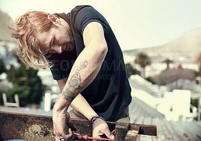 Buy stock photo Cropped shot of a handsome young man working outside on his roof