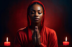 African American woman praying. Hands folded against red backdrop. Religion Concept.