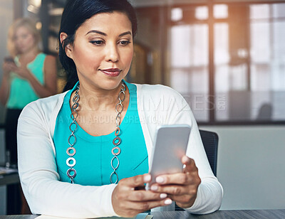 Buy stock photo Shot of a businesswoman using a phone at her desk with her colleagues in the background