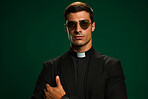 Studio portrait of young priest. Dark green backdrop. Religion concept.