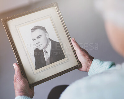 Buy stock photo Cropped shot of a senior woman looking at an old black and white photo of a man