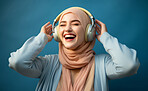 Happy muslim girl wearing headphones in studio portrait. Religion concept.