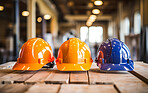 Multicolour construction hard hats stacked on table. Safety at work concept.