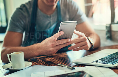 Buy stock photo Cropped shot of an unrecognizable man using on his cellphone in his coffee shop