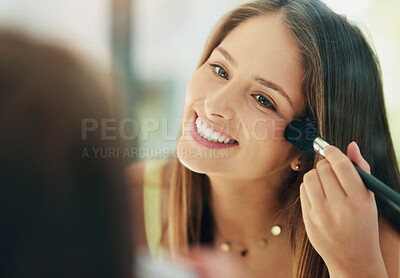 Buy stock photo Shot of an attractive young woman applying makeup to her face with a brush