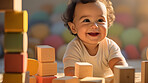Portrait of a happy toddler playing with building blocks at kindergarten or playroom.