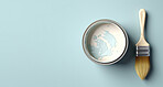 Top view of open can of paint with paint brush. Copy space. Pastel blue backdrop.