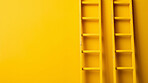 Double ladders leaning agains yellow wall. Copy space. Business, success, concept.