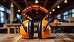 Close up of orange earmuffs on table in workshop. Safety, construction concept.