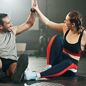 Fitness couple, high five and personal trainer with woman client to  celebrate achievement, success and goal after exercise. Man and woman  together at gym for partnership, health and wellness workout Stock Photo