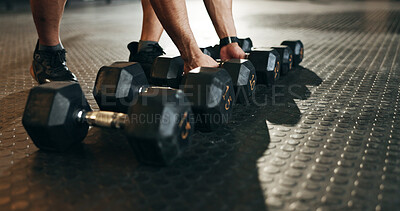 Fitness, athlete and closeup of dumbbells in gym for exercise, workout and sports training. Hands of strong bodybuilder lifting heavy weights on ground in wellness club for muscle, power or challenge