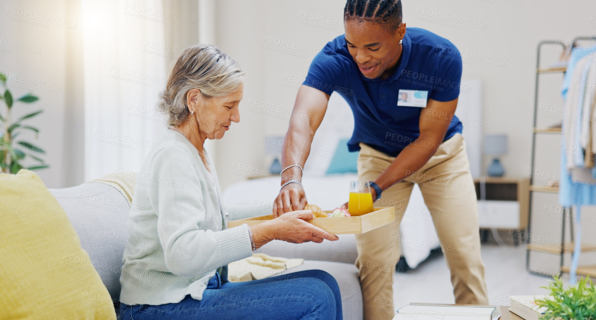 Buy stock photo Breakfast, assisted living and retirement with a old woman on a sofa in the living room of her home. Morning, food and a nurse black man serving a meal to an elderly patient in a care facility