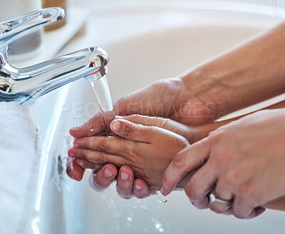 Buy stock photo Closeup shot of a mother helping her little girl wash her hands at the bathroom sink