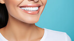 Closeup of woman with a beautiful smile for dental care against a blue background