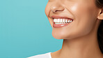 Closeup of woman with a beautiful smile for dental care against a blue background