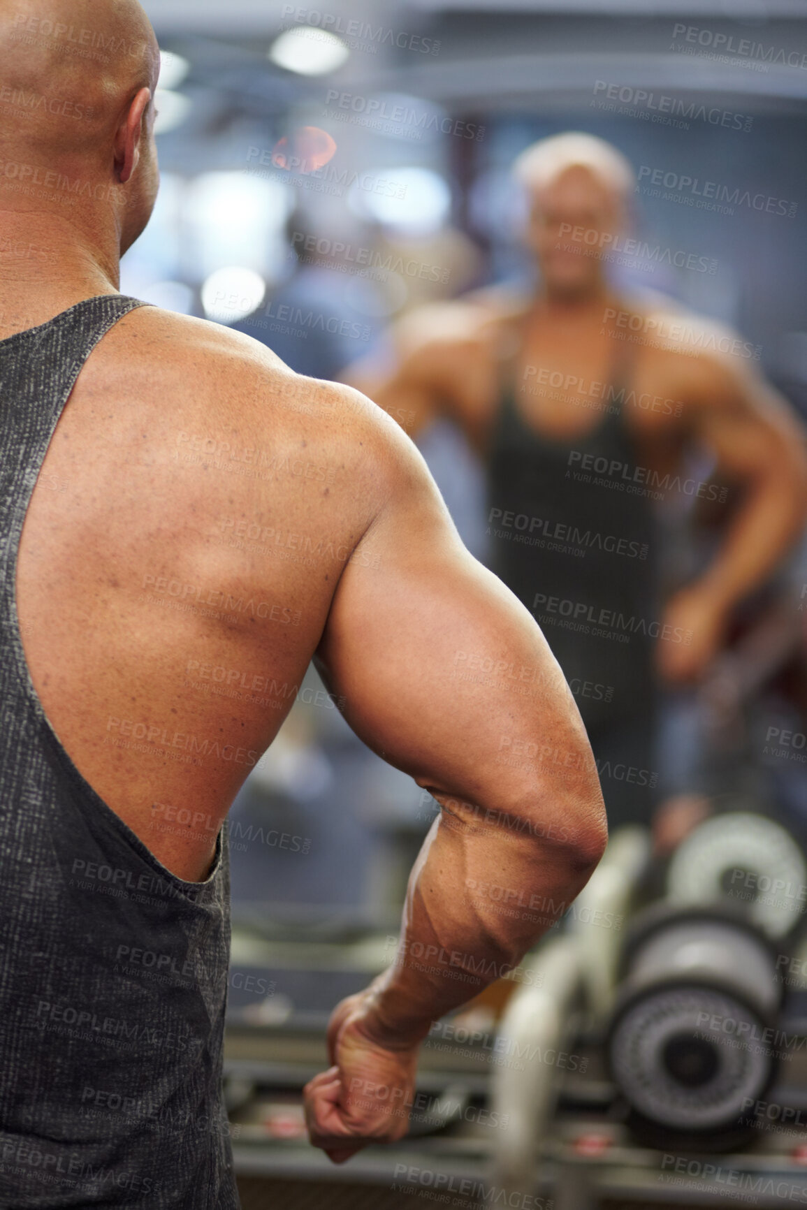 Buy stock photo A muscular bodybuilder flexing his muscles while watching his reflection in the mirror