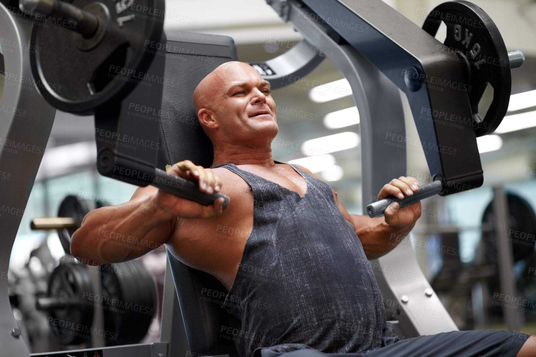Buy stock photo Shot of a male bodybuilder using exercise equipment at the gym