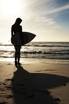 Buy stock photo Silhouette, woman surfer on beach sand and ocean, exercise outdoor and healthy with surfboard and scenic sea view. Sports, shadow and sun with female person in nature and ready to surf for fitness