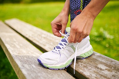 Buy stock photo Cropped shot of a young woman tying her shoelaces