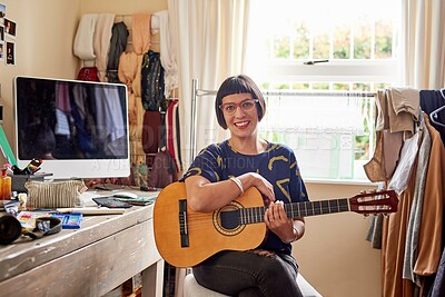 Buy stock photo Portrait of a stylish young woman sitting in her eclectic toom playing a guitar