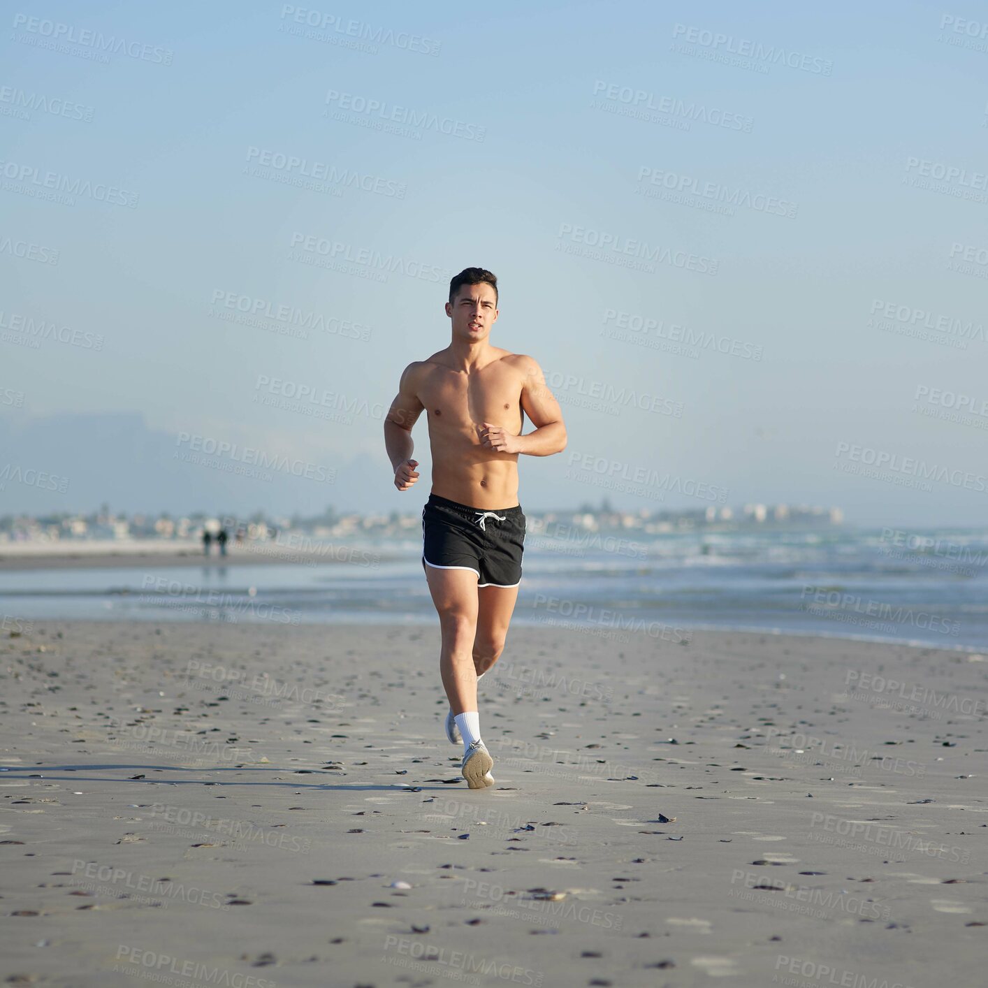 Buy stock photo Full length shot of a handsome young man running on the beach