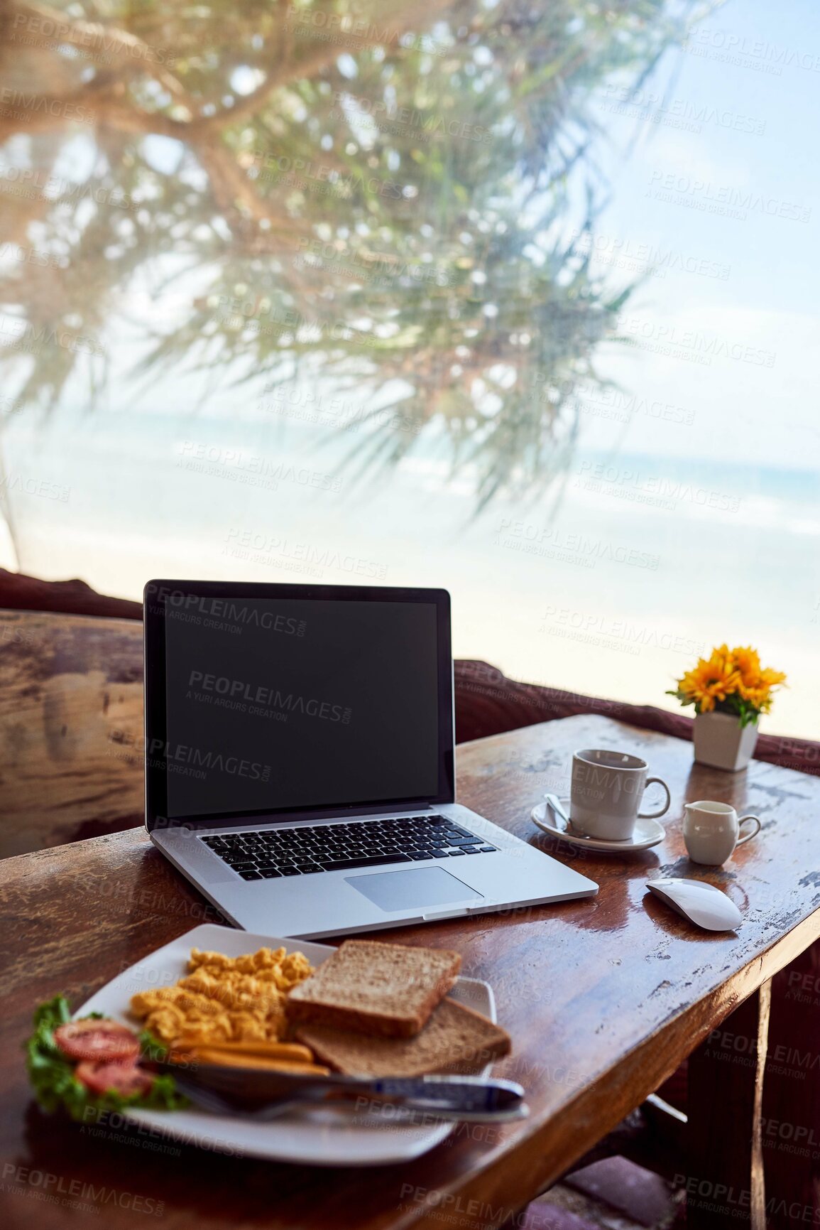 Buy stock photo Shot of a laptop and freshly made breakfast on a table with a view of the beach in the background