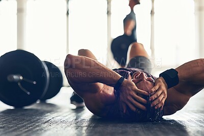 Buy stock photo Shot of a muscular young man looking exhausted after an intense workout in a gym