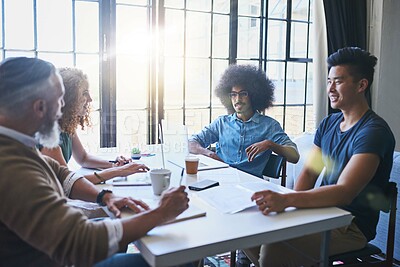 Buy stock photo Shot of a group of cheerful creative businesspeople having a meeting around a table together inside the office during the day