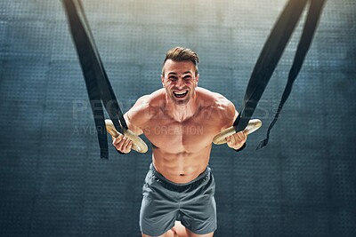 Buy stock photo Shot of a muscular young man working out with gymnastic rings at the gym