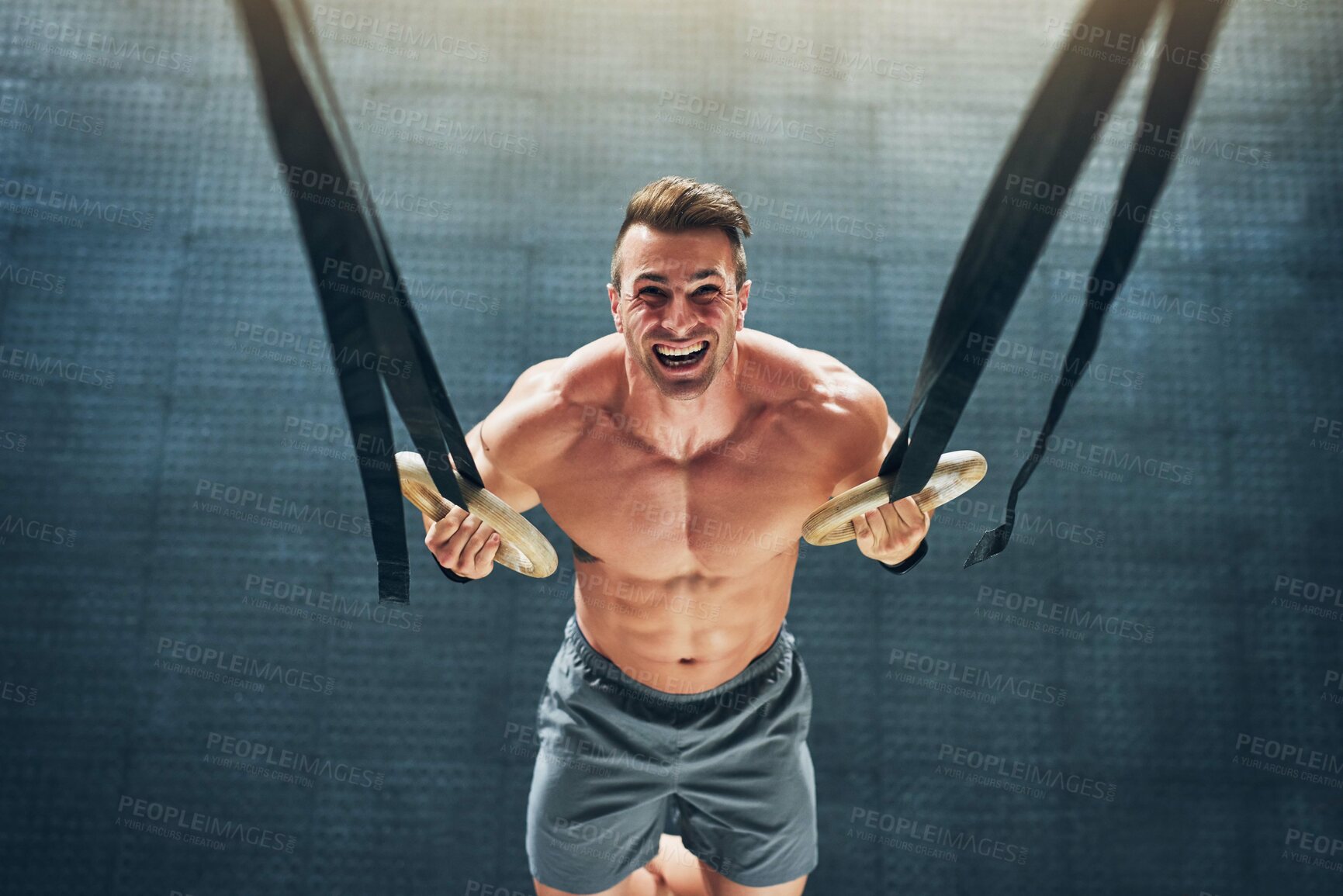 Buy stock photo Shot of a muscular young man working out with gymnastic rings at the gym