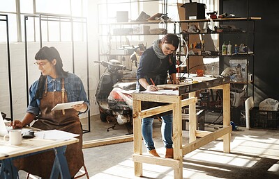 Buy stock photo Cropped shot of two attractive young creative female artisans working in their workshop