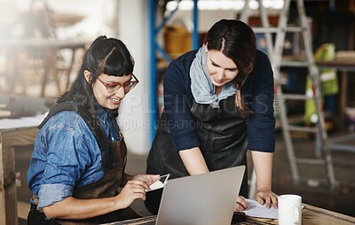Buy stock photo Cropped shot of two attractive young creative female artisans working on a laptop in their workshop