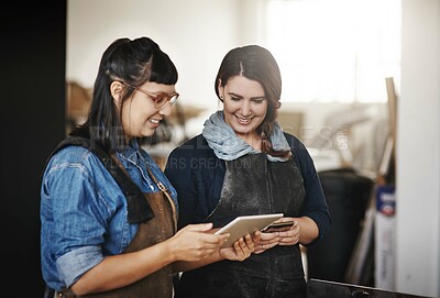 Buy stock photo Cropped shot of two attractive young creative female artisans working on a tablet in their workshop