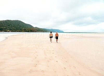 Buy stock photo Rearview shot of two young men walking along the beach