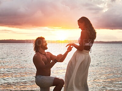 Buy stock photo Shot of a young man proposing to his girlfriend at the beach