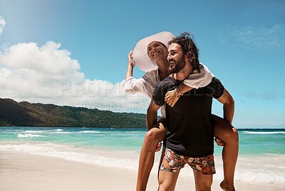 Buy stock photo Cropped shot of a cheerful young couple giving each other piggyback rides while walking on a beach outside during the day