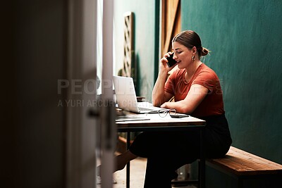 Buy stock photo Cropped shot of an attractive young businesswoman sitting alone and using her cellphone while using her laptop