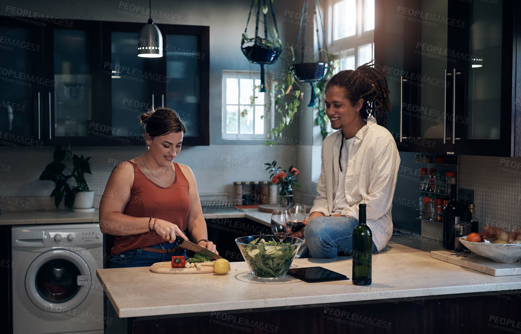 Buy stock photo Shot of a young couple bonding in the kitchen while preparing a salad