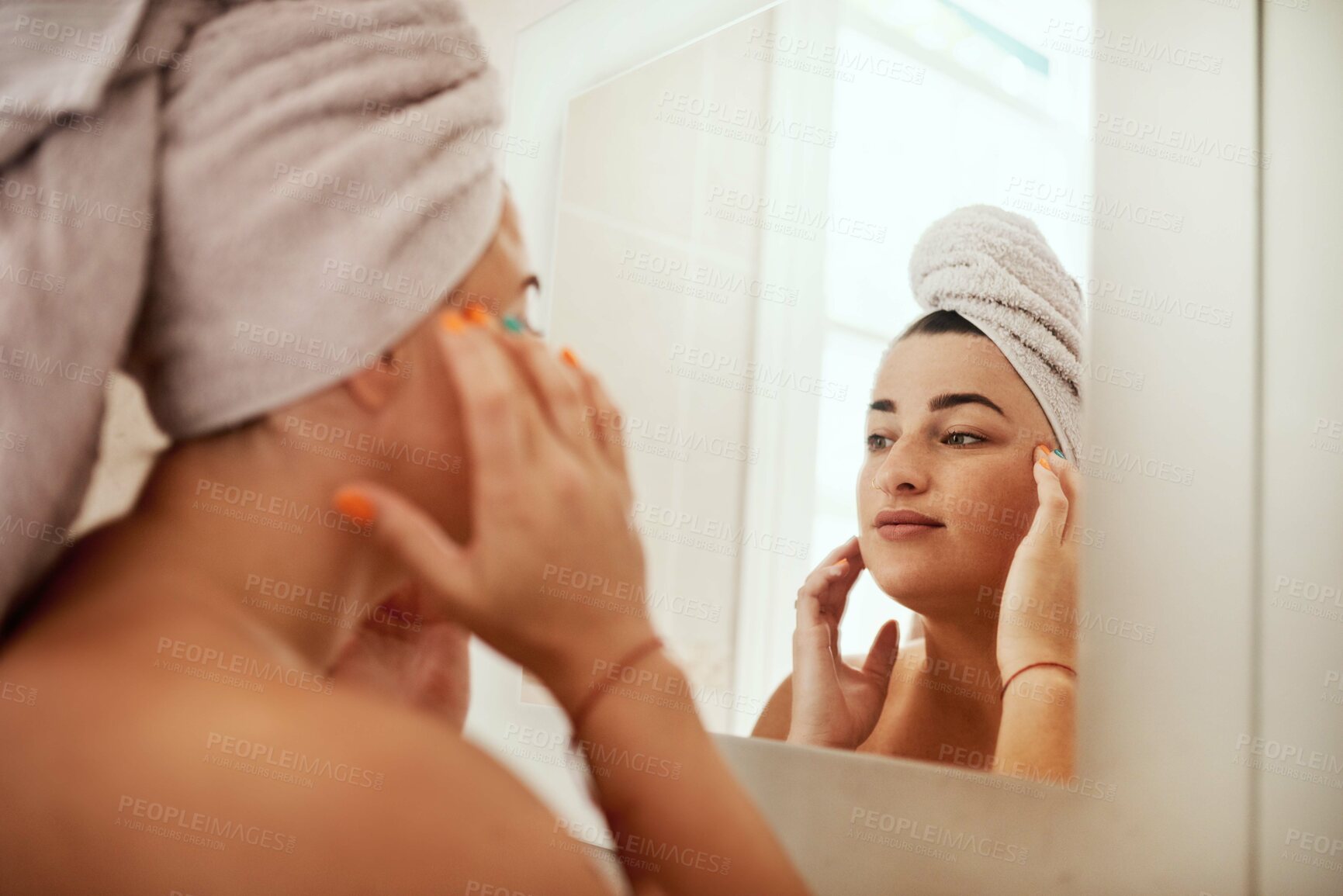 Buy stock photo Shot of an attractive young woman inspecting her face in the bathroom mirror